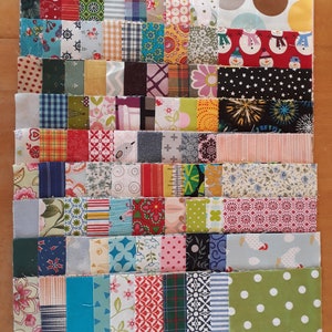 Könnte beinhalten: Eine Sammlung von Stoffquadraten in verschiedenen Farben und Mustern, darunter Blumen, geometrische Muster und Karos. Die Quadrate sind in Reihen angeordnet und bilden ein Patchwork-Quilt-Design.