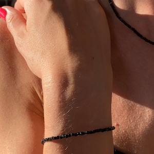 May include: A black beaded bracelet on a person's wrist.