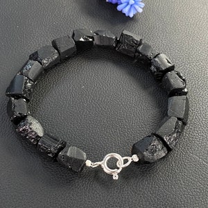 May include: Black Tourmaline bracelet made with rough, natural stones. The bracelet has a silver clasp.