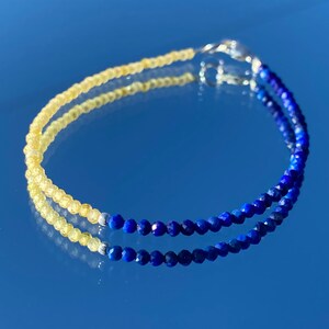 May include: A delicate bracelet with two rows of beads. The top row is made of yellow citrine beads, while the bottom row is made of blue lapis lazuli beads. The bracelet is secured with a silver clasp.