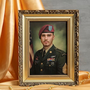 May include: A framed portrait of a soldier in a military uniform. He is wearing a maroon beret with a blue and white insignia. The soldier is standing in front of an American flag. The frame is gold with ornate details.