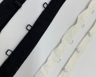 May include: Two strips of bra strap fabric, one black and one white, with metal hooks and eyes for adjusting the fit.