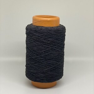 May include: A spool of black elastic cord wound around a brown cardboard tube.