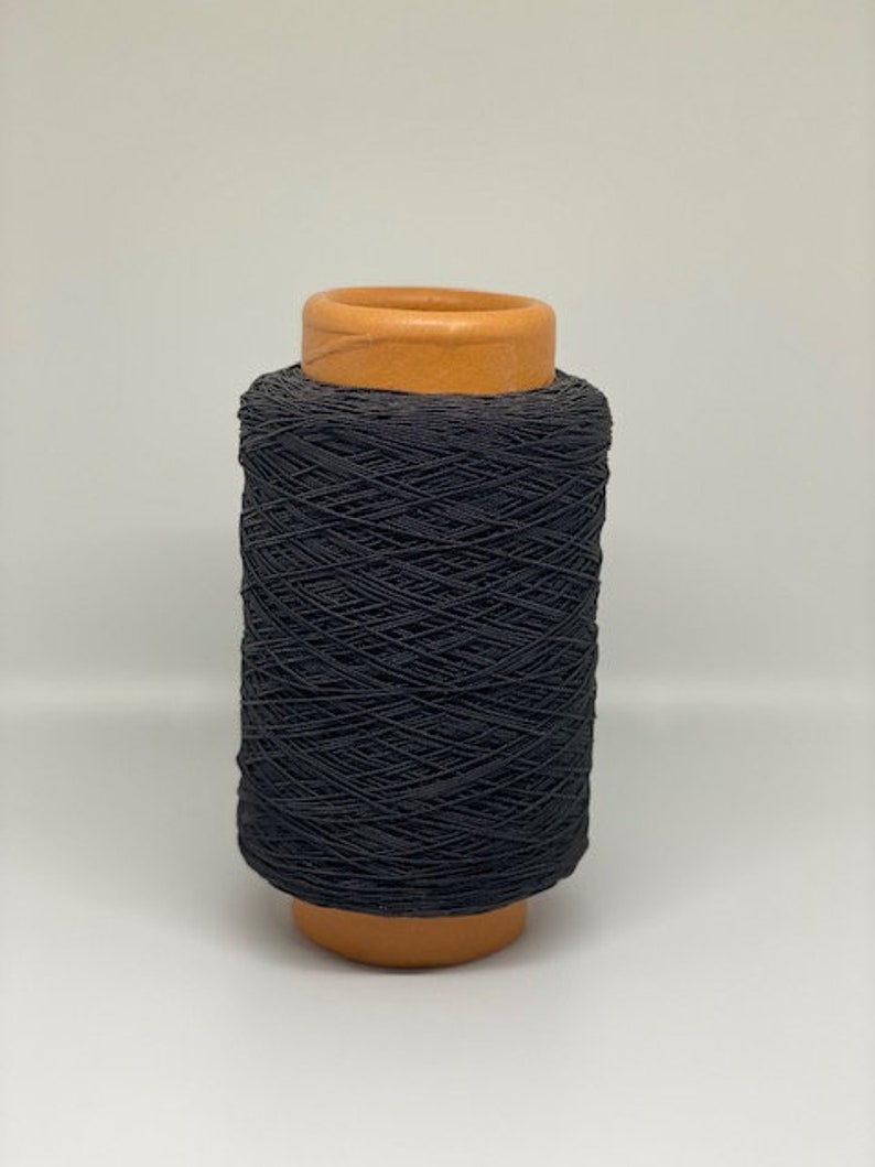May include: A spool of black elastic cord wound around a brown cardboard tube.