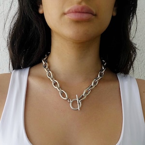 Puede incluir: Un collar de cadena de plata con cierre de palanca. La cadena es gruesa y tiene un eslab&oacute;n ovalado y grueso.