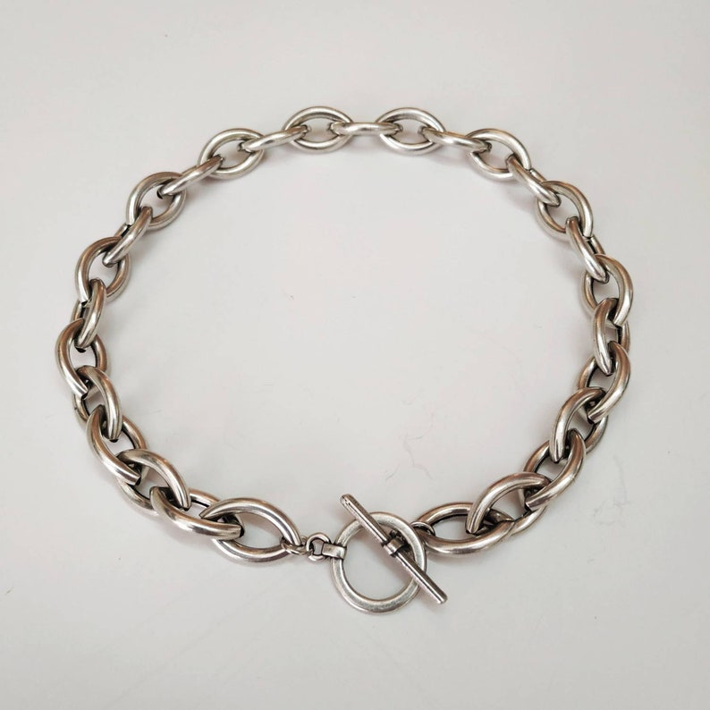 Puede incluir: Un collar de cadena de plata con cierre de palanca. La cadena est&aacute; hecha de eslabones gruesos de forma ovalada.