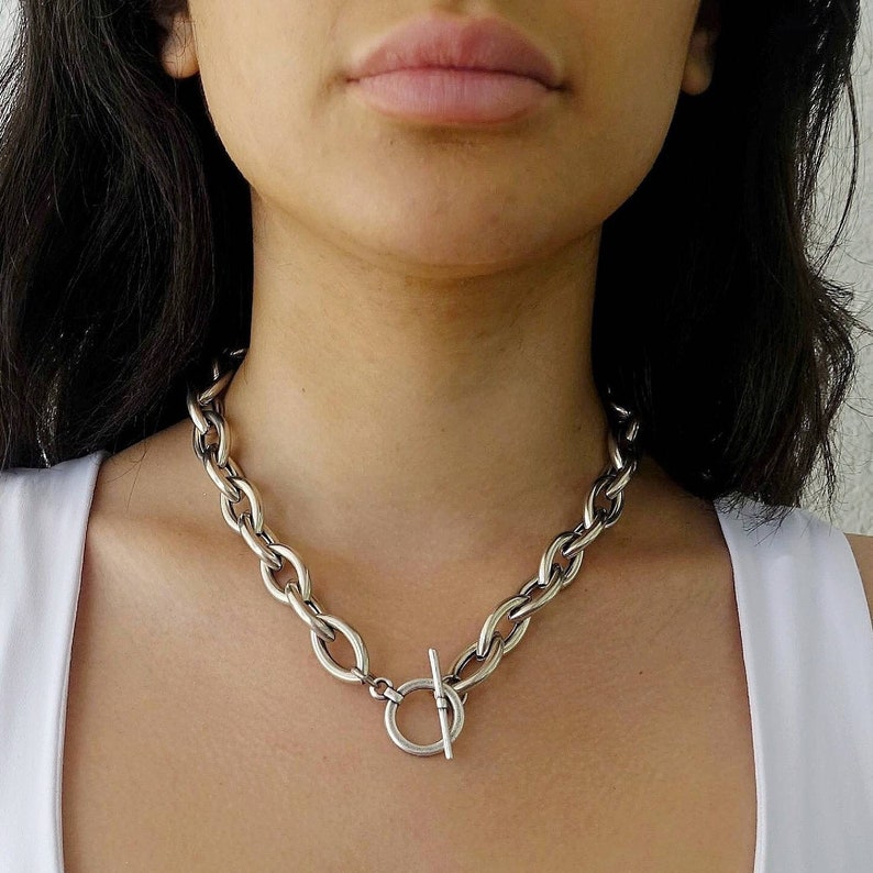 Puede incluir: Un collar de cadena de plata con cierre de palanca. La cadena es gruesa y tiene un eslab&oacute;n ovalado y grueso.