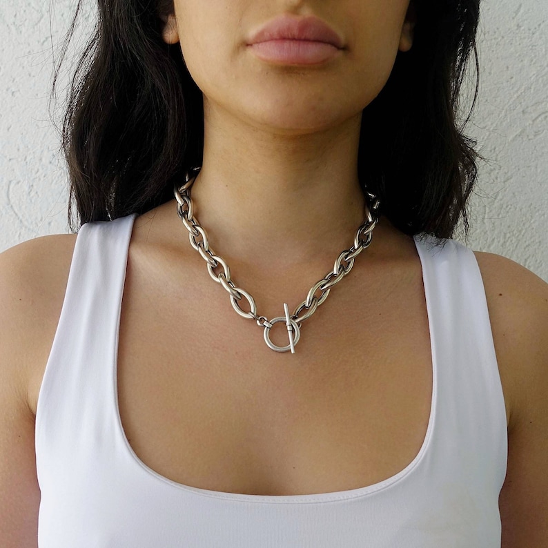 Puede incluir: Un collar de cadena de plata con cierre de palanca. La cadena es gruesa y tiene un eslab&oacute;n ovalado y grueso.