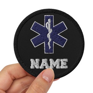May include: Black embroidered patch with a blue star of life and a caduceus, with the word "NAME" below.