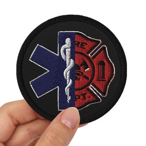 Peut inclure: Un écusson brodé noir et rouge avec une étoile de la vie et un symbole de pompier. L'écusson est tenu dans une main.