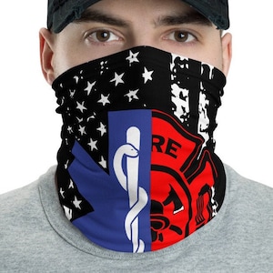 Könnte beinhalten: Eine schwarze und blaue Gesichtsmaske mit einem abgenutzten amerikanischen Flaggenmuster. Die Maske zeigt auf der linken Seite ein medizinisches Symbol und auf der rechten Seite ein Feuerwehrsymbol. Die Maske wird von einer Person mit einer schwarzen Baseballkappe getragen.
