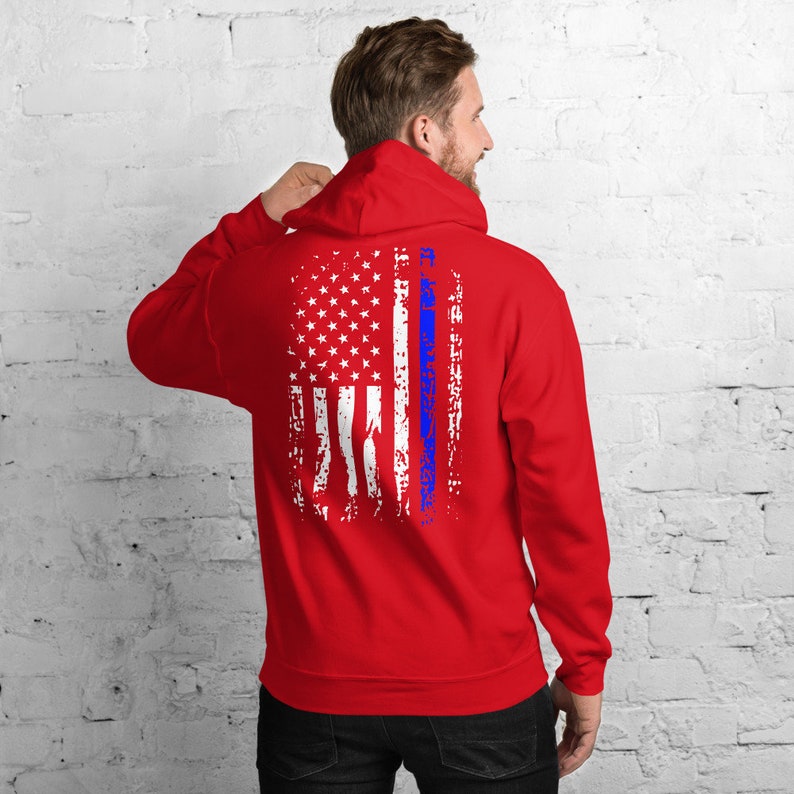 Puede incluir: Sudadera con capucha roja con un dise&ntilde;o de bandera estadounidense desgastado y una fina l&iacute;nea azul en el centro.