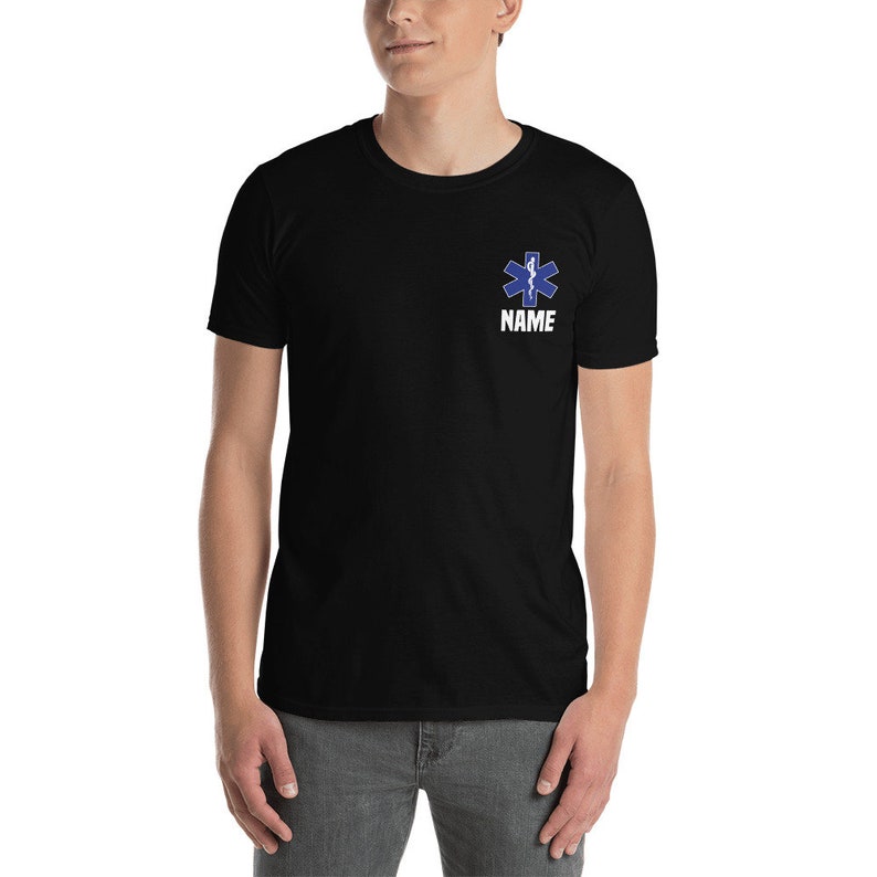 May include: Black t-shirt featuring a blue Star of Life emblem and the word "NAME" in white text. The emblem is a six-pointed star with a snake and staff design, commonly associated with emergency medical services.