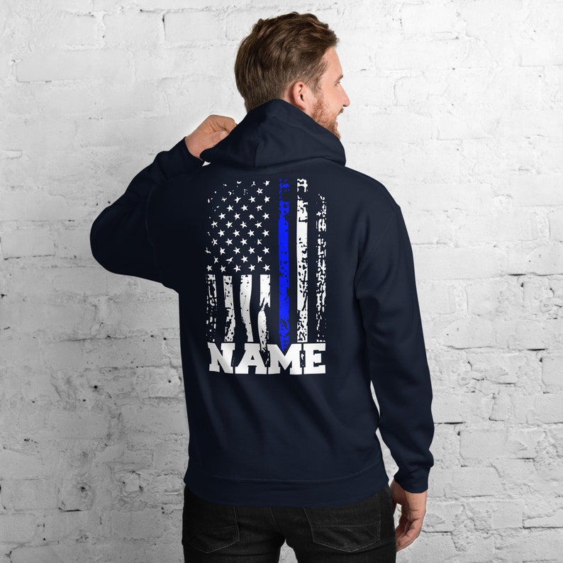 Puede incluir: Sudadera con capucha azul marino con un dise&ntilde;o de bandera estadounidense desgastado con una l&iacute;nea azul delgada y la palabra "NAME" impresa debajo de la bandera.