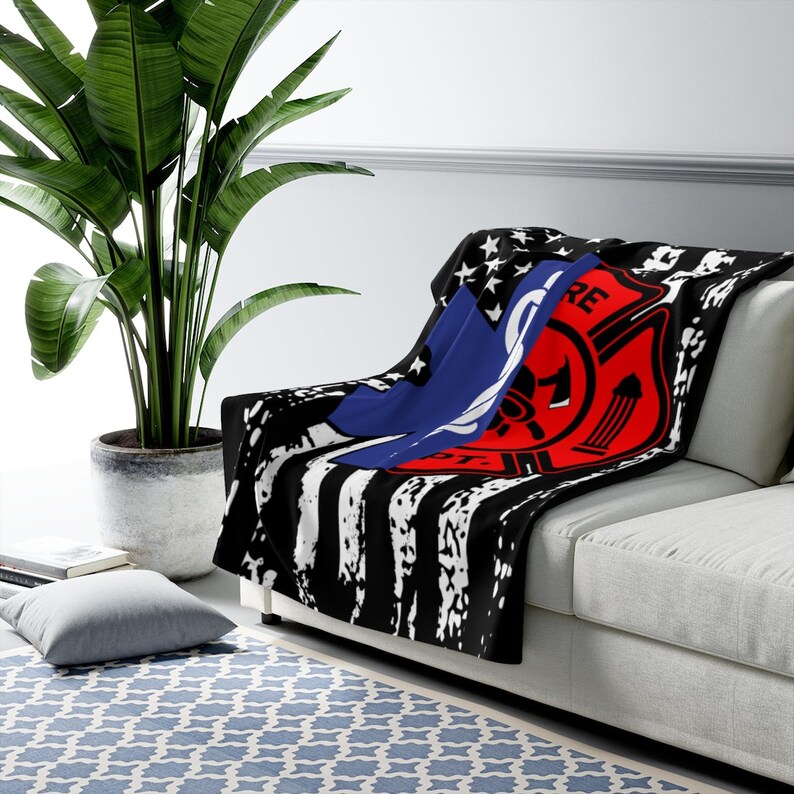 May include: Black and white distressed American flag throw blanket with a red and blue firefighter emblem. The emblem features a fire axe, a hose, and the word "FIRE" in red.