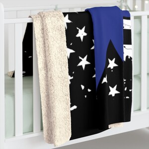 May include: A black and white American flag throw blanket with a blue stripe down the side. The blanket has a soft, plush texture and is perfect for snuggling up on the couch.