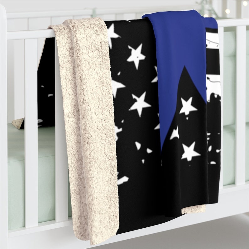 May include: A black and white American flag throw blanket with a blue stripe down the side. The blanket has a soft, plush texture and is perfect for snuggling up on the couch.