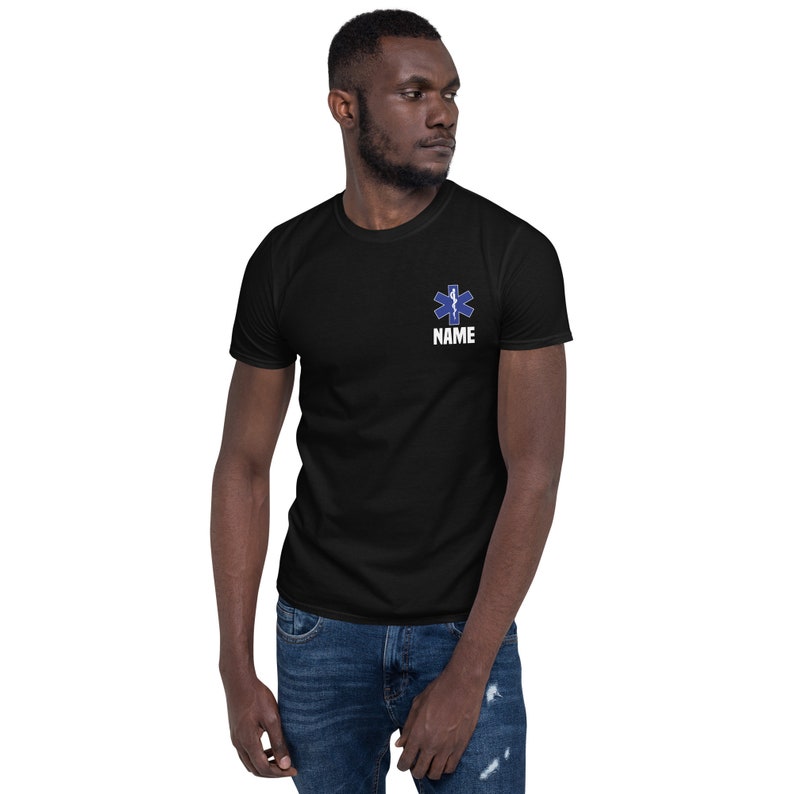 May include: Black t-shirt with a blue and white Star of Life emblem and the word "NAME" printed below it. The shirt is short-sleeved and made of a soft material.