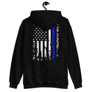 Puede incluir: Sudadera con capucha negra con un dise&ntilde;o de bandera estadounidense desgastado con una fina l&iacute;nea azul en el centro.
