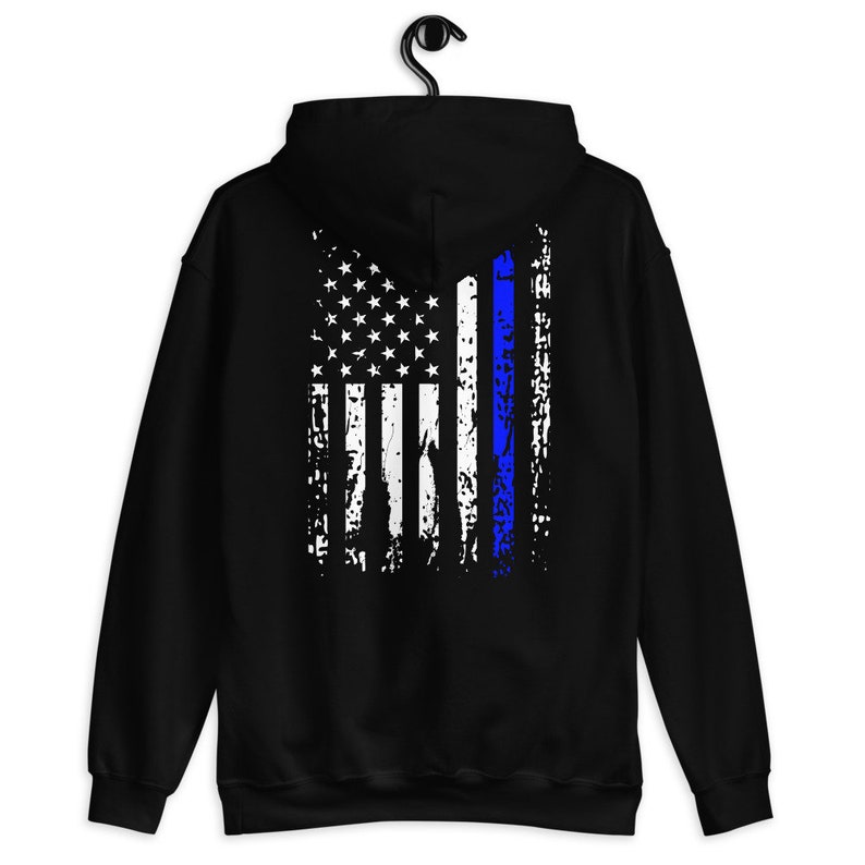 Puede incluir: Sudadera con capucha negra con un dise&ntilde;o de bandera estadounidense desgastado con una fina l&iacute;nea azul en el centro.