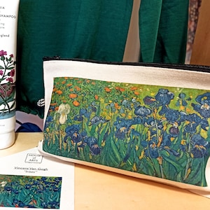 Può includere: Una pochette con cerniera in tela bianca con una stampa del dipinto "Iris" di Vincent Van Gogh. La pochette è accanto a due bottiglie di prodotti per la cura dei capelli, una con un'etichetta verde e bianca e l'altra con un'etichetta rosa e bianca. Le etichette sulle bottiglie hanno il testo "Vivaiodays" e "Organic World Series" stampato su di esse.