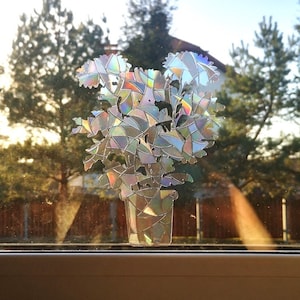 May include: A window with a view of trees and a sticker of a flower bouquet in a pot on the glass.