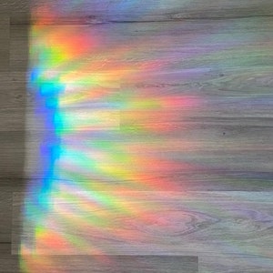 Puede incluir: Un efecto de prisma arco&iacute;ris en un suelo de madera. La luz crea un patr&oacute;n colorido de rojo, naranja, amarillo, verde, azul, a&ntilde;il y violeta.