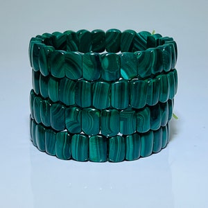 Puede incluir: Un conjunto de cuatro pulseras de piedra de malaquita verde. Cada pulsera está hecha de cuentas rectangulares con un acabado liso y pulido.