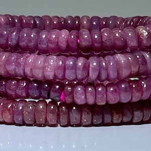 Peut inclure: Un brin de perles de rubis roses, avec une finition lisse et polie. Les perles sont rondes et ont une forme légèrement allongée. Le brin est composé de plusieurs rangées de perles, créant un effet de superposition.