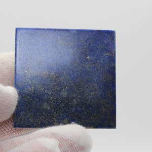 Op de afbeelding: Een vierkant stuk gepolijst lapis lazuli met een diepblauwe kleur en vlekken van gouden pyriet.