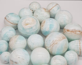 May include: A collection of blue and white celestite spheres of various sizes. The spheres are smooth and polished, with a natural, swirling pattern.