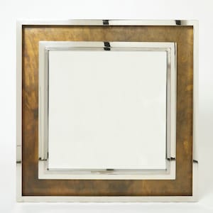 May include: A square mirror with a double frame. The inner frame is silver and the outer frame is a brown wood with a silver trim.