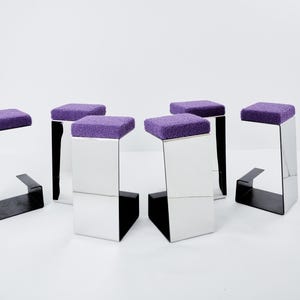 Puede incluir: Cinco taburetes tapizados en color morado con marcos de metal espejado. Los taburetes están dispuestos en círculo.