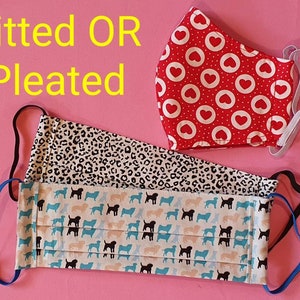 May include: Three fabric face masks, one with a red background and white hearts, one with a black and white leopard print, and one with a white background and black dog silhouettes. The text "Fitted OR Pleated" is written in yellow at the top of the image.