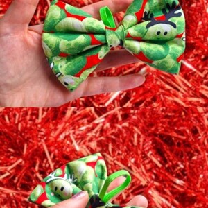 May include: A red bow tie with a green sprout pattern. The sprouts have a reindeer face on them. The bow tie is tied with a green elastic band.