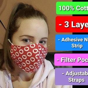 May include: A red face mask with white hearts and circles. The mask is made of 100% cotton and has 3 layers. It also has an adjustable nose strip, a filter pocket, and adjustable straps.
