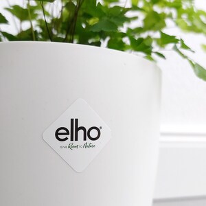 May include: White plastic plant pot with a diamond-shaped sticker that says "elho GIVE Room to Nature".