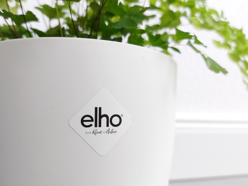 May include: White plastic plant pot with a diamond-shaped sticker that says "elho GIVE Room to Nature".
