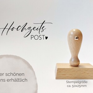 Könnte beinhalten: Holz Stempel mit Griff und rechteckiger Basis. Der Stempel lautet "Hochzeits POST" mit einem kleinen Herzsymbol. Der Stempel ist ca. 50x25mm groß. Der Text "In vier schönen Designs erhältlich" ist im Bild sichtbar.