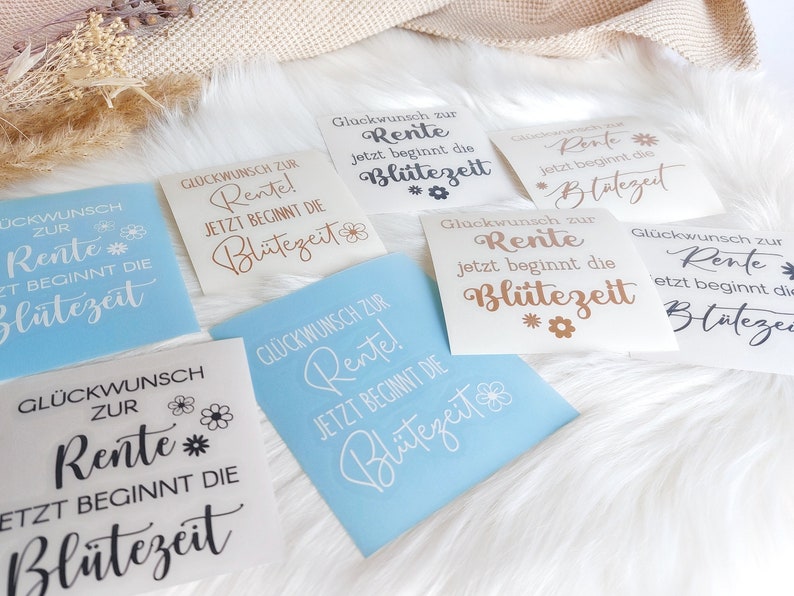 May include: Six different versions of a retirement announcement sign. The signs are all white with black, brown, or gold lettering. The text on the signs reads "Gl&uuml;ckwunsch zur Rente! Jetzt beginnt die Bl&uuml;tezeit" which translates to "Congratulations on your retirement! Now the bloom time begins".
