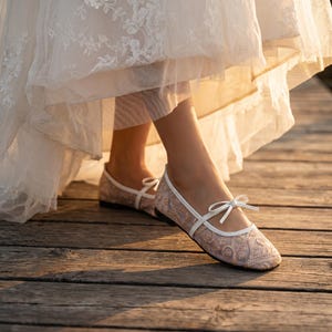 Delicate lace bridal flats with transparent floral mesh and strap styles, minimalist wedding ballet shoes in ivory tones, soft comfortable footwear for bride displayed on neutral fabric background, multiple elegant variations