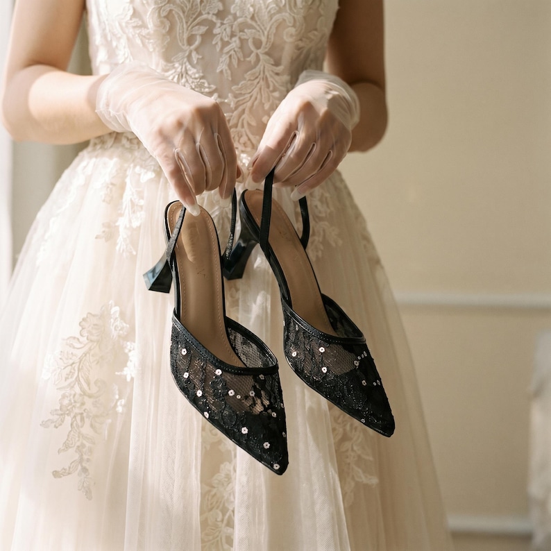 Elegant lace slingback heels with pointed toe and sculpted heel, available in white and black colors, styled in romantic bridal setting with pearls, lace fabric, and floral details for wedding or special occasion wear.