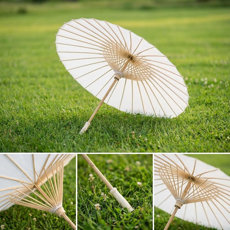 May include: A white paper parasol with a bamboo handle and ribs, resting on green grass. The parasol is open, showcasing its delicate design. The handle has a white grip. The image is well-lit, highlighting the parasol's texture and form.