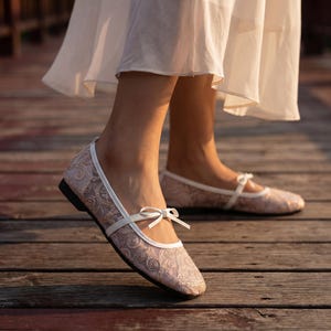 Delicate lace bridal flats with transparent floral mesh and strap styles, minimalist wedding ballet shoes in ivory tones, soft comfortable footwear for bride displayed on neutral fabric background, multiple elegant variations