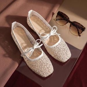 Delicate lace bridal flats with transparent floral mesh and strap styles, minimalist wedding ballet shoes in ivory tones, soft comfortable footwear for bride displayed on neutral fabric background, multiple elegant variations