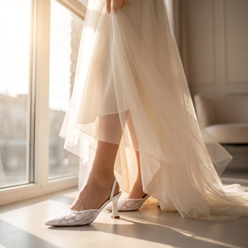 Elegant lace slingback heels with pointed toe and sculpted heel, available in white and black colors, styled in romantic bridal setting with pearls, lace fabric, and floral details for wedding or special occasion wear.