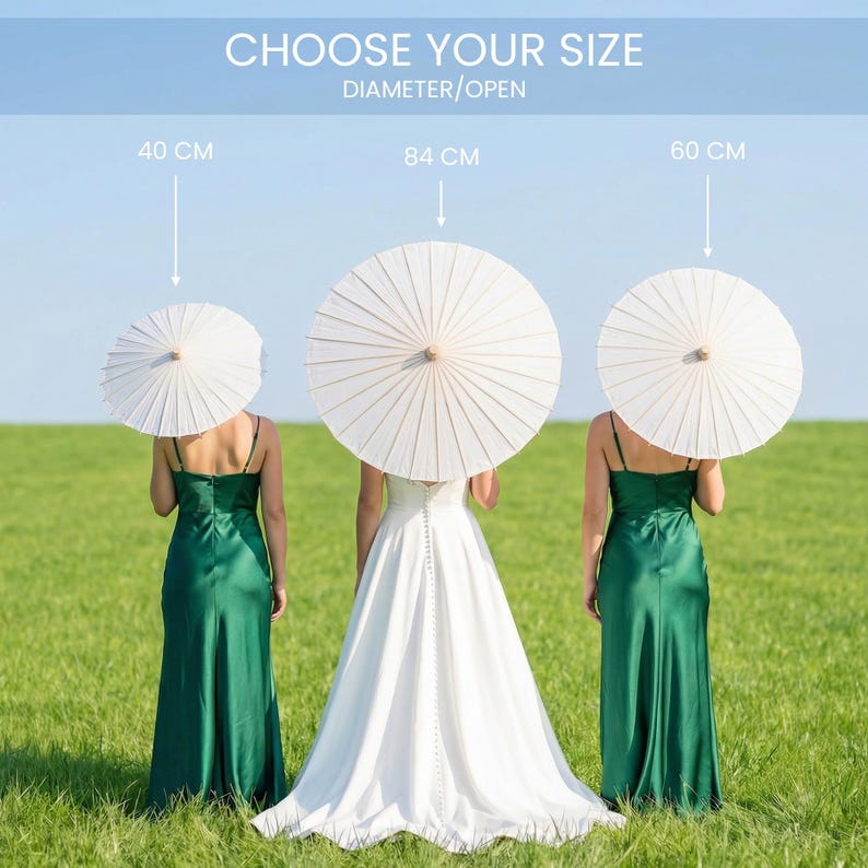 May include: Three women stand in a green field, each holding a white parasol. The parasols are 15.7, 33.1, and 23.6 inches in diameter. The text at the top says "CHOOSE YOUR SIZE" and "DIAMETER/OPEN". One woman wears a white dress, the others wear green dresses.