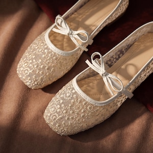 Delicate lace bridal flats with transparent floral mesh and strap styles, minimalist wedding ballet shoes in ivory tones, soft comfortable footwear for bride displayed on neutral fabric background, multiple elegant variations
