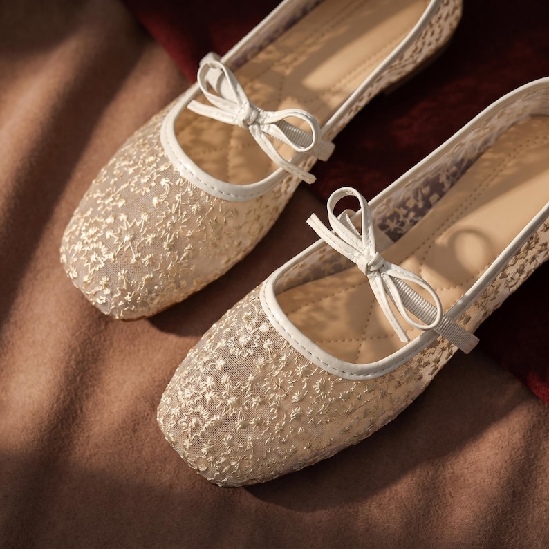 Delicate lace bridal flats with transparent floral mesh and strap styles, minimalist wedding ballet shoes in ivory tones, soft comfortable footwear for bride displayed on neutral fabric background, multiple elegant variations
