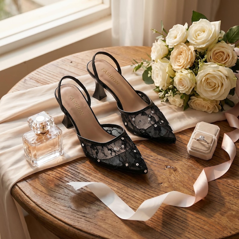Elegant lace slingback heels with pointed toe and sculpted heel, available in white and black colors, styled in romantic bridal setting with pearls, lace fabric, and floral details for wedding or special occasion wear.